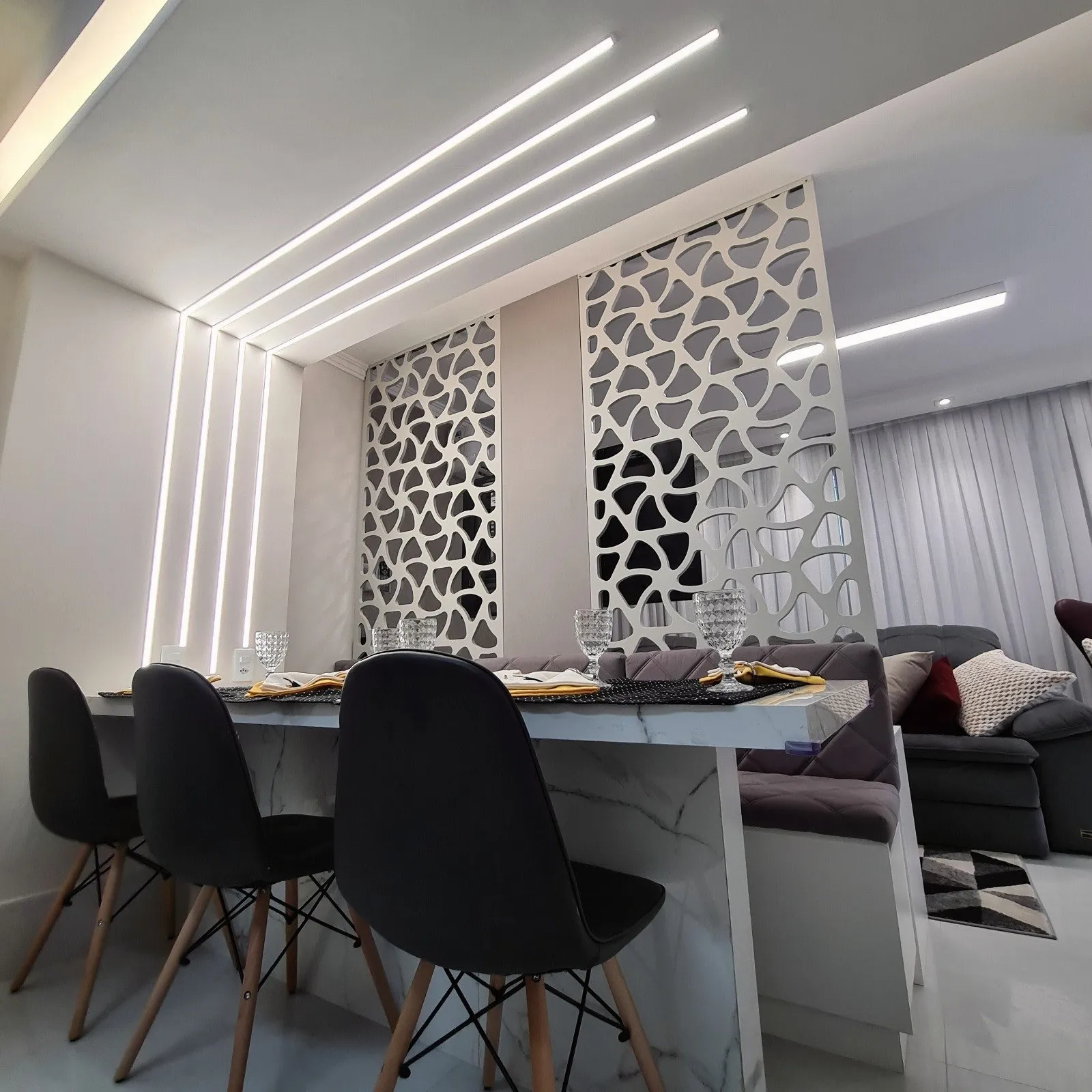 Sala de jantar com divisória vazada branca e linhas de LED no teto