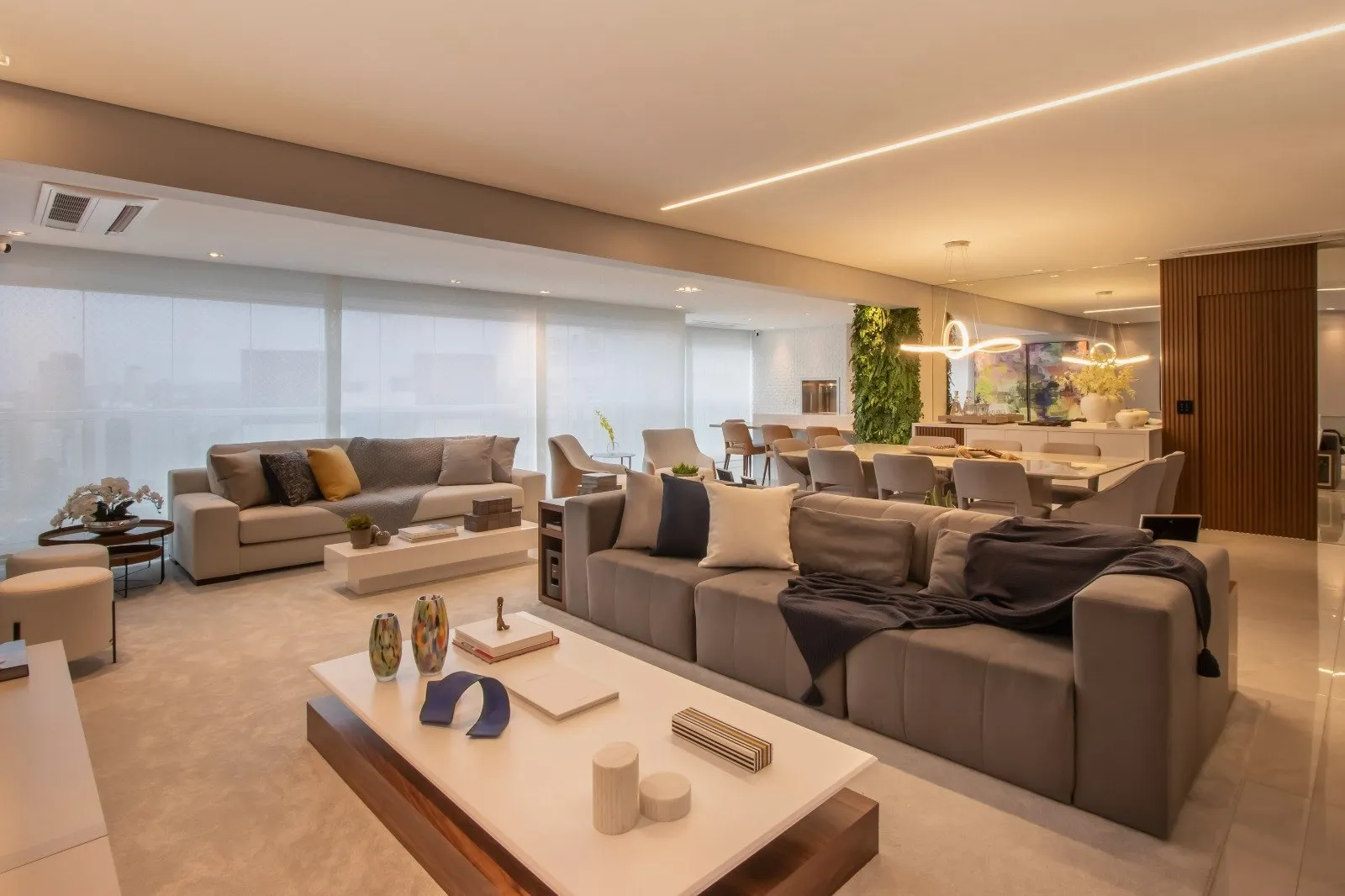 Sala ampla com sofás longos, mesa de centro e iluminação embutida